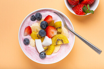 Healthy breakfast or dessert yogurt bowl with fresh banana, strawberry, blueberry, cocos, kiwi top...