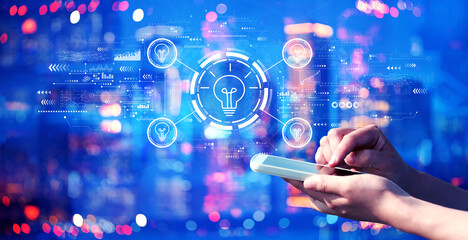 Idea light bulb theme with person using a smartphone in a city at night