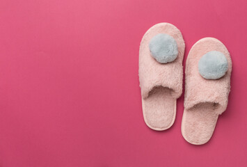 Soft pink slippers on color background, top view