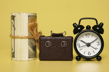 A picture of fake roll money, briefcase miniature and alarm clock. Rising living cost concept.