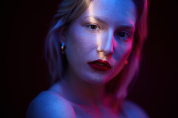 Portrait of a serious young blond woman isolated on magenta background. Viva magenta.