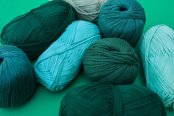 Close view of turquoise skein of yarn surrounded with green ones