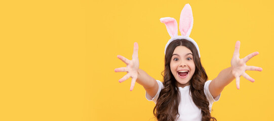 happy amazed kid in bunny ears reach hands on yellow background. Easter child horizontal poster. Web banner header of bunny kid, copy space.