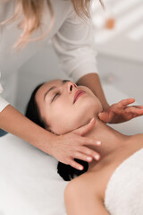 Crop masseuse massaging neck of female customer in salon