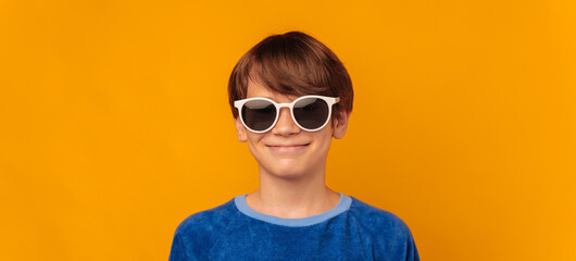 Banner shot of a shy smiling boy who is wearing cool white sunglasses.