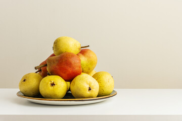 A plate overflowing with delicious ripe pears on a white shelf