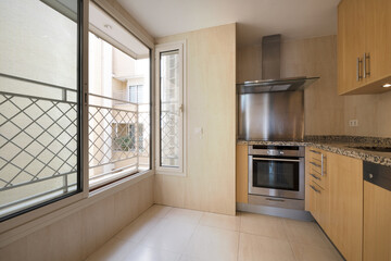 Furnished kitchen with two L-shaped walls with light wood cabinets, pink granite countertops,...
