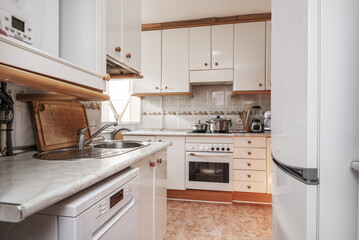 kitchen with light furniture with wooden handles, wooden details on skirting boards and moldings...