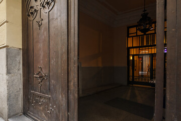 Portal of a vintage building with a metal door of brown color and a stone facade