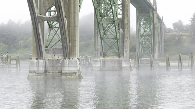 Drone Aerial Video Yaquina Bay Bridge Newport Oregon Coast Fog 01 Time Lapse of Fog receding from water level view of columns supporting Yaquina Bay Bridge, Newport, Oregon