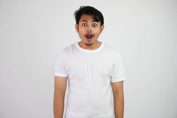 Obraz premium Close up of shocked young Asian man with open mouth and looking at camera wearing white t shirt isolated on white background