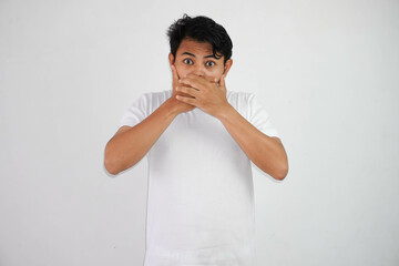 Portrait of scared young Asian man covering mouth with hands wearing white t shirt isolated on white background