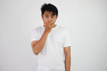 Portrait of scared young Asian man covering mouth with hands wearing white t shirt isolated on white background