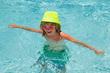Child playing in swimming pool. Kids holidays and vacation concept. Happy little boy swim in blue water.