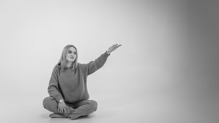 portrait of a young, emotional girl stretching her hands to the camera in a flirtatious mood, gesturing with her hands, empty space, wearing jeans and sweater on an isolated white background