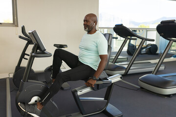 African american senior man using stationary bike at the gym
