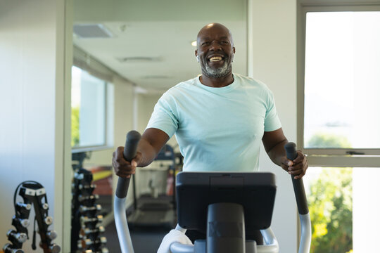 Portrait of african american senior man using elliptical machine at the gym