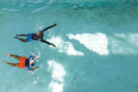 Aerial view of african american senior couple swimming together in the swimming pool