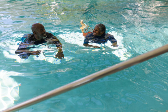African american senior couple swimming together in the swimming pool