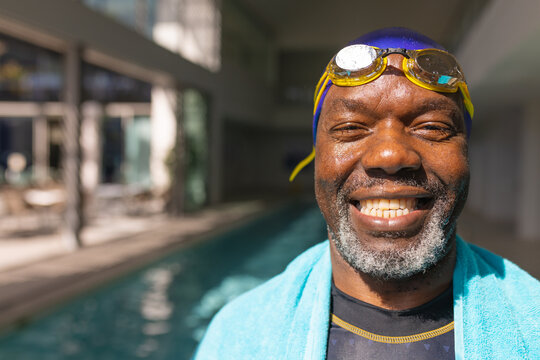 Portrait of african american senior man smiling while standing by the swimming pool