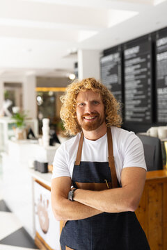 Portrait of happy caucasian male barista with a rms crossed in cafe