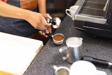 Biracial female barista wearing apron and preparing coffee in cafe