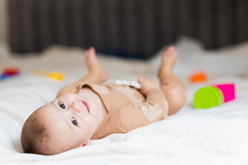 baby up to a year old, lying on the bed among toys