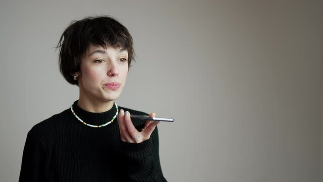 Shocked woman talking on her smartphone. Young gen z girl during a conversation via phone call over gray background. Studio portrait. High quality 4k footage