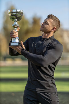 Athletic man holding ruach goblet at sports stadium outdoors