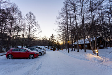 Snow covered cars and woods log cabins with snowy rooftop, deep snow outside, morning serene natural landscape in Japan on January 2023.