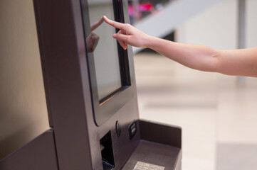 Faceless woman using touchscreen ATM. 