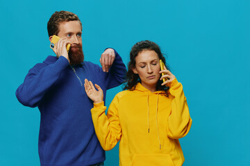 Woman and man cheerful couple with phones in their hands crooked smile cheerful, on blue background. The concept of real family relationships, talking on the phone, work online.