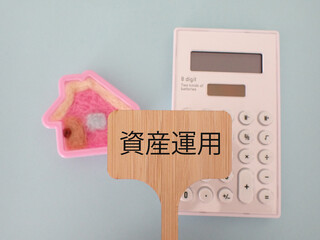プラカードに資産運用の単語、可愛い家と電卓