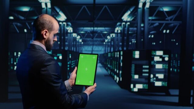 Database admin analyzing greenscreen display on tablet, doing web system check in server room. IT engineer using mockup copyspace display with isolated chroma key. Tripod shot.
