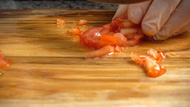 The cook cuts tomatoes on a cutting board.