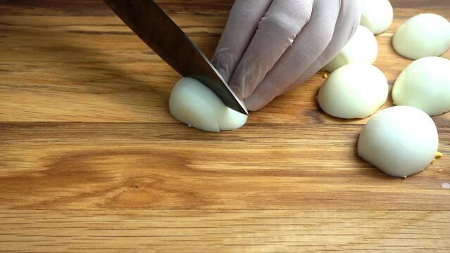 The cook cuts egg on a cutting board.