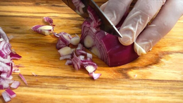 Chefs hands with knife cutting the onion on the wooden