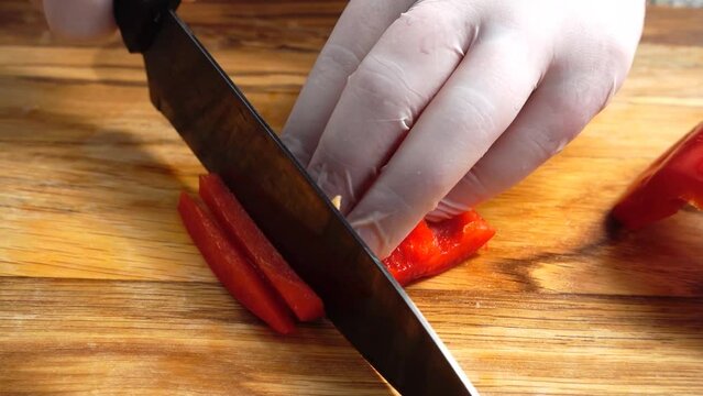 Slicing sweet pepper on wooden cutting board.