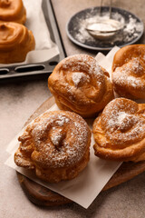Many delicious profiteroles with powdered sugar on grey table, closeup