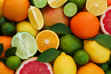 Fototapeta na wymiar Different fresh citrus fruits and leaves as background, top view.