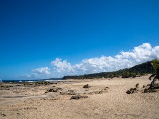 Panoramic views of a sandy beach in the tropics with mountain views and beautiful blue skies