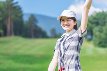 ゴルフ場でゴルフをするゴルフウェアを着たゴルファーの女性（カメラ目線）　撮影協力：あづみ野カントリークラブ