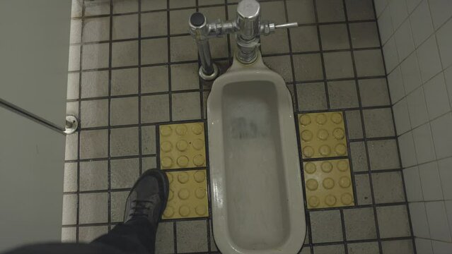 This POV video shows a foreign Japanese floor toilet being flushed by the users foot.