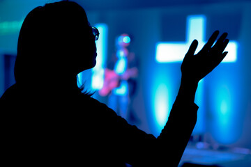 Silueta de persona clamando a Dios mientras canta