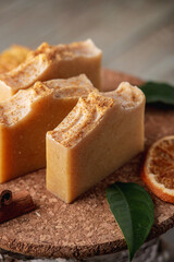 Natural soap and slices of oranges, cinnamon and green leaves on the wooden table. Concept of eco cosmetics and interesting useful hobby
