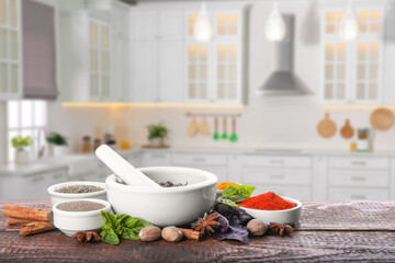 Mortar and different spices on wooden table in kitchen. Space for text