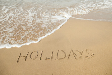 Fototapeta premium Holidays lettering on the beach with wave and clear blue sea. 