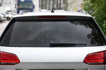 Wiper cleaning raindrops from car rear windshield outdoors