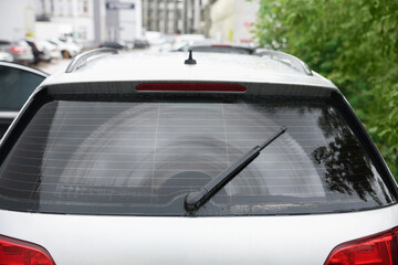 Wiper cleaning raindrops from car rear windshield outdoors - obrazy, fototapety, plakaty