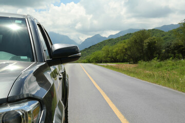 Car driving on asphalt road near mountains, closeup. Space for text